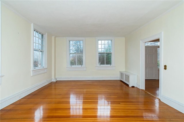 unfurnished room with crown molding, radiator heating unit, and wood-type flooring