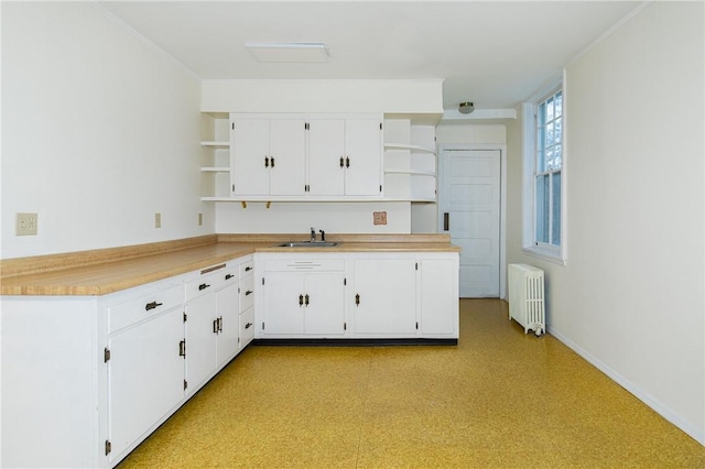 kitchen featuring radiator heating unit, white cabinets, and sink