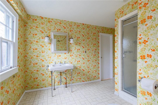 bathroom with a wealth of natural light, a shower with shower door, and sink