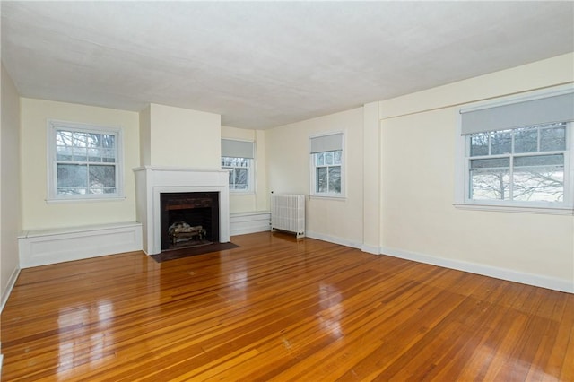 unfurnished living room with hardwood / wood-style flooring and radiator heating unit