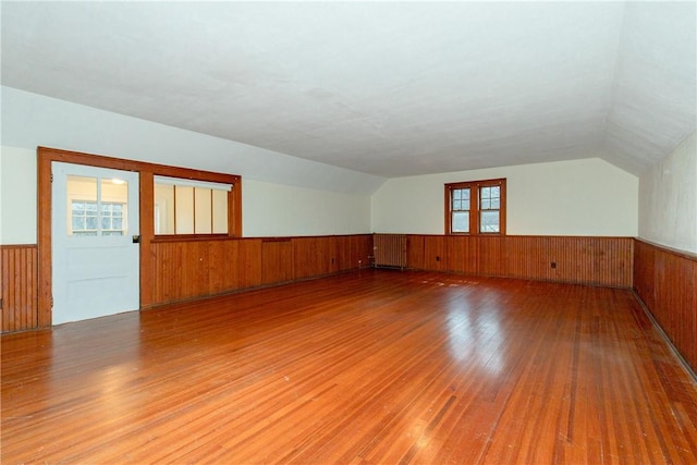 unfurnished room with wood-type flooring, wooden walls, and vaulted ceiling