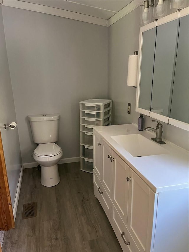 bathroom featuring toilet, hardwood / wood-style floors, vanity, and ornamental molding