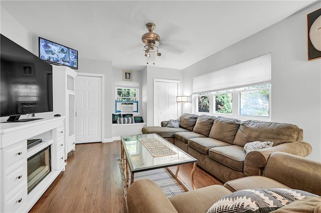 living room with cooling unit, plenty of natural light, dark wood-type flooring, and ceiling fan