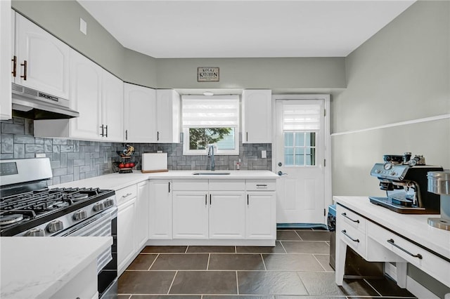 kitchen featuring white cabinets, backsplash, stainless steel gas range oven, and sink