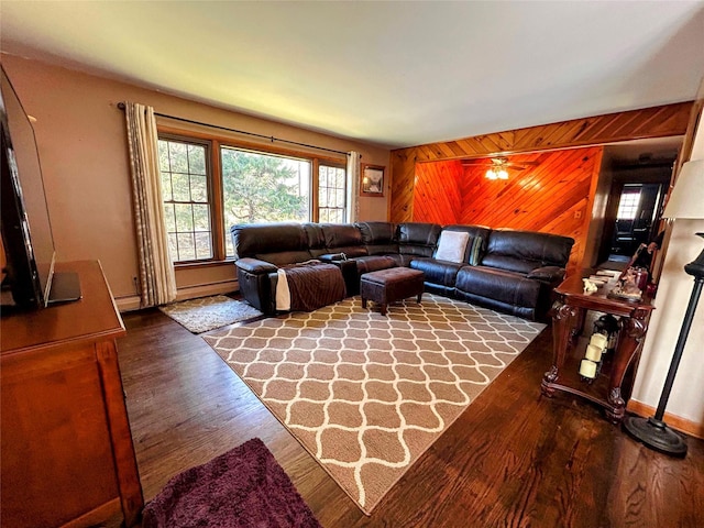 living room with hardwood / wood-style floors, ceiling fan, and wood walls