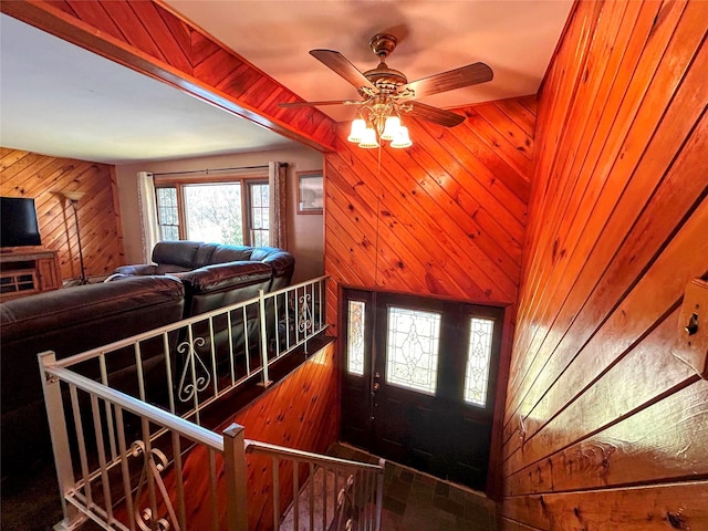 foyer entrance with wooden walls and ceiling fan