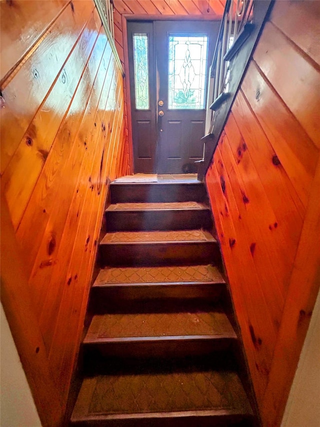 stairway featuring wood walls