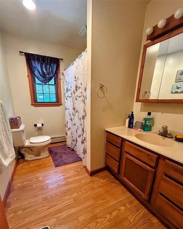 bathroom featuring vanity, toilet, wood-type flooring, and a baseboard heating unit