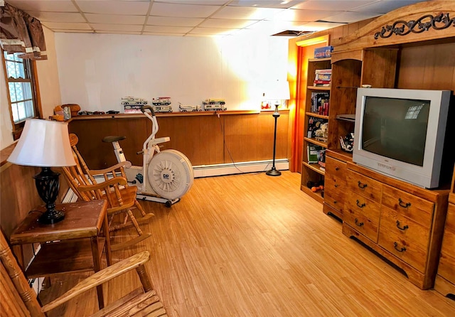 sitting room featuring light wood-type flooring, a baseboard radiator, and a drop ceiling