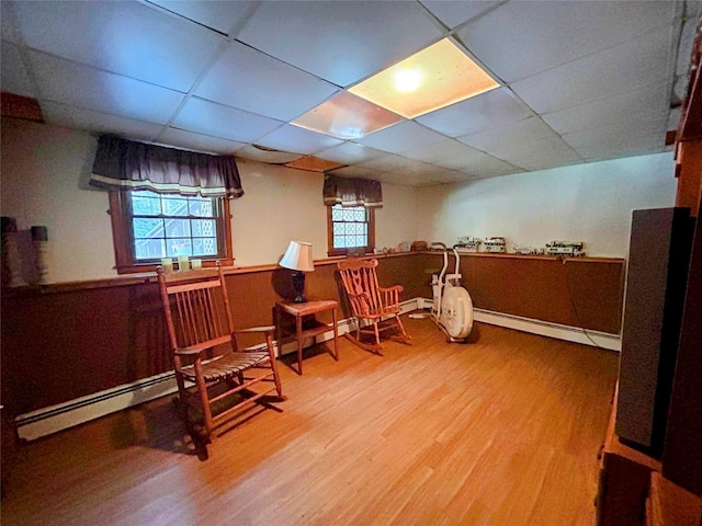 living area featuring a paneled ceiling, a baseboard radiator, and hardwood / wood-style flooring