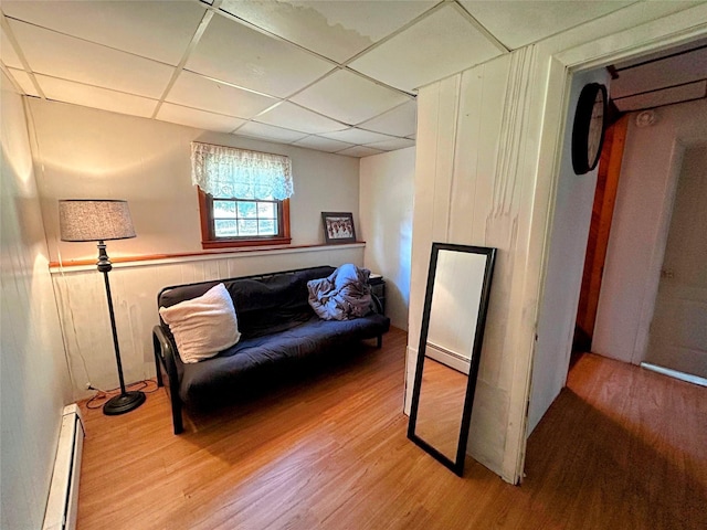 sitting room with a paneled ceiling, light hardwood / wood-style floors, and baseboard heating