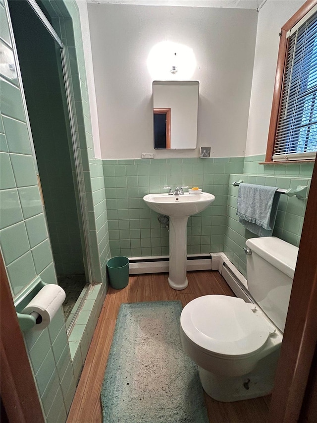 bathroom featuring hardwood / wood-style floors, toilet, tile walls, and a shower with shower door