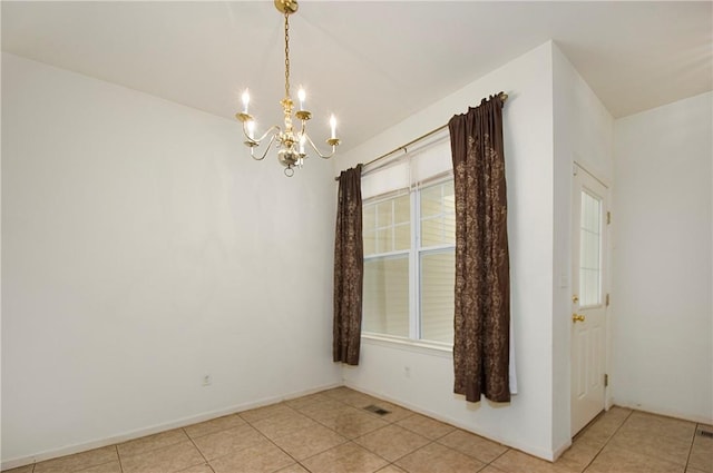 spare room featuring light tile patterned floors and an inviting chandelier