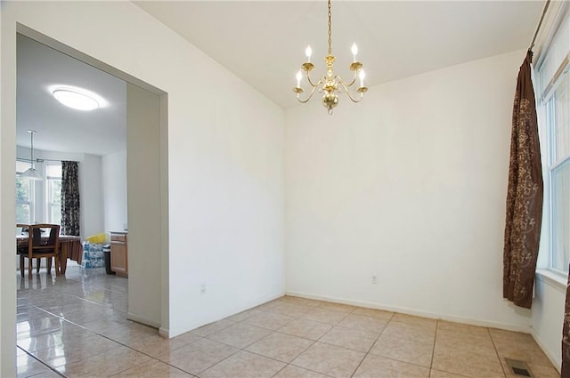 tiled empty room with a notable chandelier