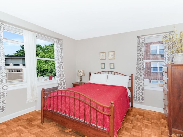 bedroom with cooling unit, multiple windows, and light parquet floors