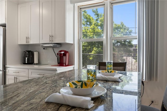 kitchen featuring stainless steel fridge, tasteful backsplash, white cabinetry, and light stone counters