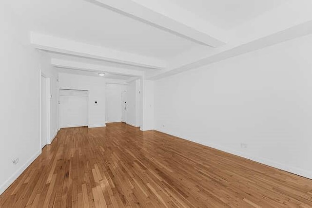 unfurnished living room featuring beamed ceiling and hardwood / wood-style flooring