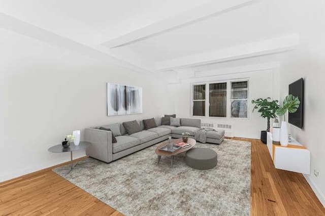 living room featuring beam ceiling, wood-type flooring, and radiator heating unit