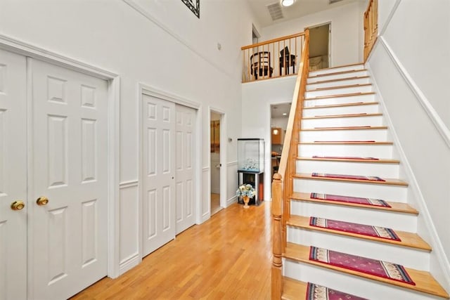 stairway with hardwood / wood-style flooring and a high ceiling