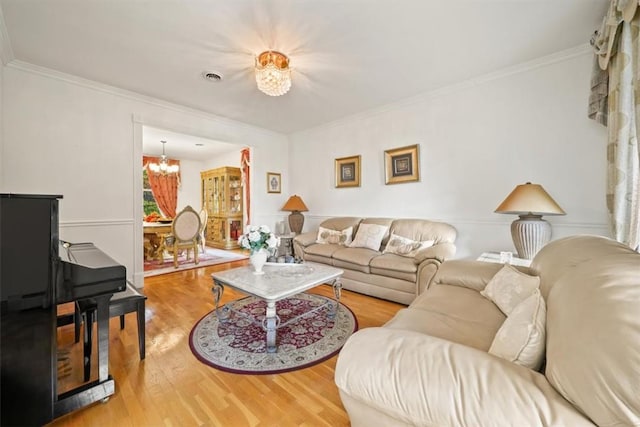 living room with hardwood / wood-style flooring, crown molding, and a notable chandelier