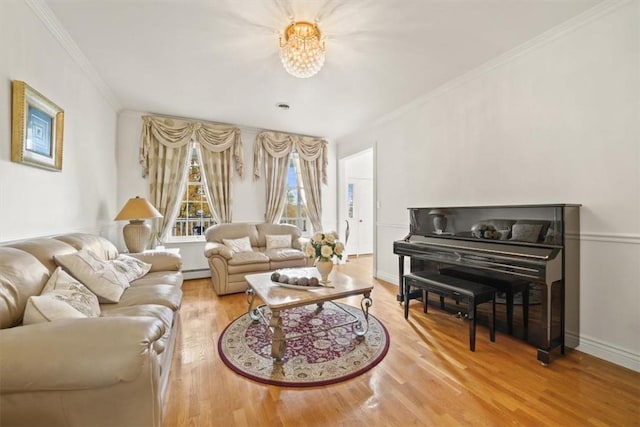 living room featuring ornamental molding, light wood-type flooring, baseboard heating, and a notable chandelier