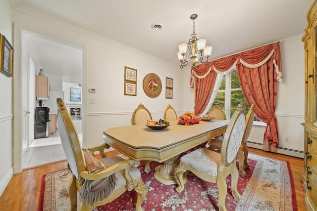 dining space featuring a baseboard heating unit, light hardwood / wood-style floors, an inviting chandelier, and crown molding