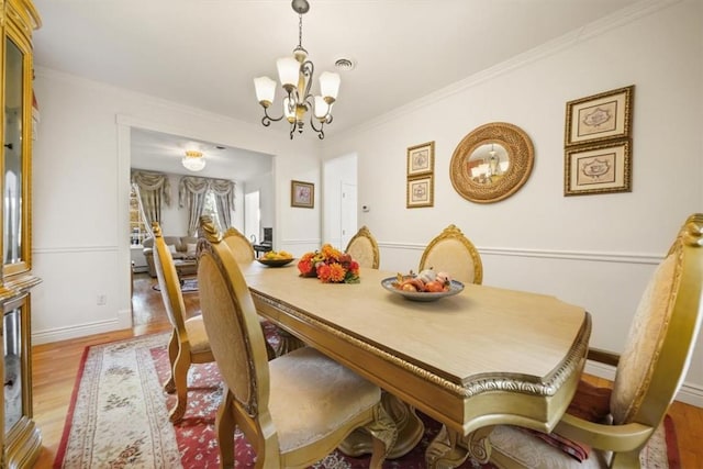 dining space featuring light hardwood / wood-style floors, ornamental molding, and an inviting chandelier