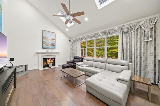 living room featuring a skylight, ceiling fan, high vaulted ceiling, and hardwood / wood-style flooring