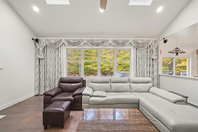 living room featuring lofted ceiling with skylight, plenty of natural light, and dark wood-type flooring