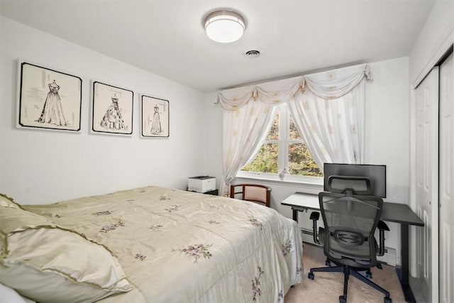 carpeted bedroom with baseboard heating and a closet