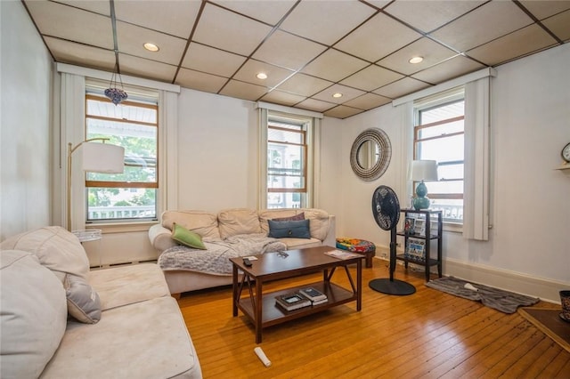 living room featuring hardwood / wood-style floors, a drop ceiling, baseboard heating, and a wealth of natural light