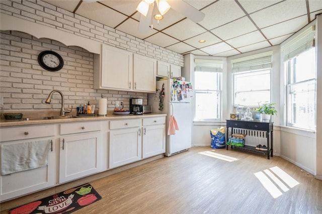 kitchen featuring white cabinets, a healthy amount of sunlight, and white refrigerator