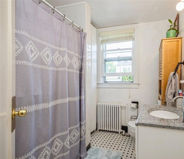 bathroom with vanity, toilet, walk in shower, and radiator