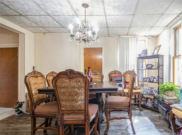 dining area with wooden walls, wood-type flooring, and a notable chandelier