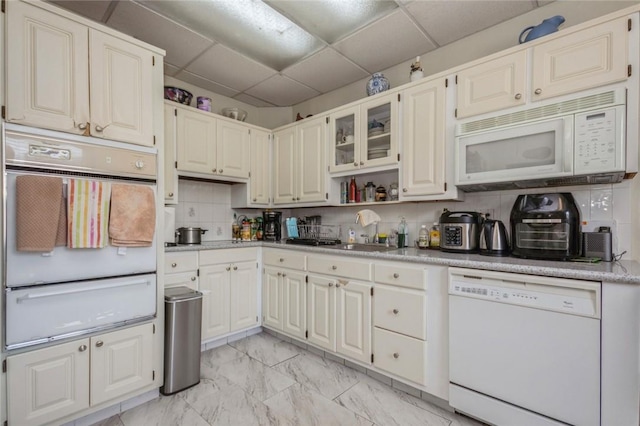 kitchen featuring a paneled ceiling, tasteful backsplash, white appliances, sink, and white cabinetry