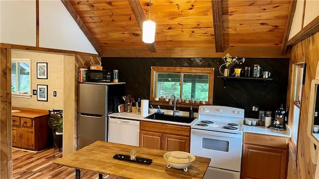 kitchen with wood walls, sink, lofted ceiling with beams, and white appliances