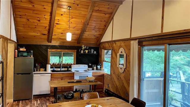 kitchen featuring wood walls, white appliances, sink, beam ceiling, and wood-type flooring