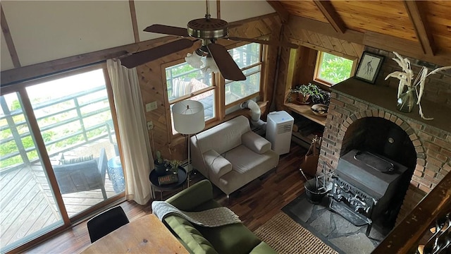 living room with ceiling fan, wood-type flooring, a fireplace, vaulted ceiling with beams, and wood walls