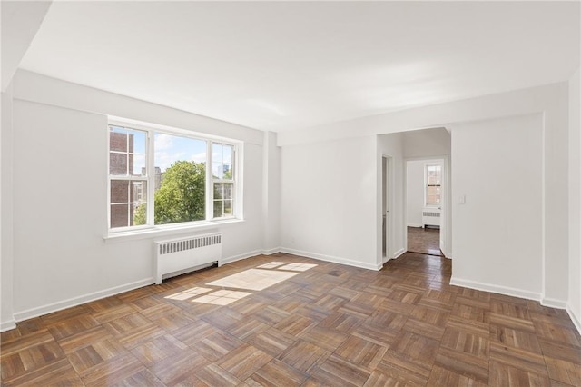 spare room with dark parquet flooring and radiator