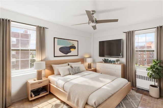 bedroom with ceiling fan, radiator heating unit, and parquet flooring