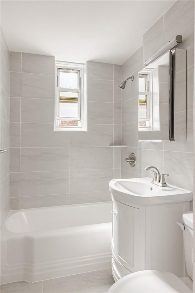 full bathroom with vanity, tiled shower / bath combo, toilet, tile walls, and tasteful backsplash