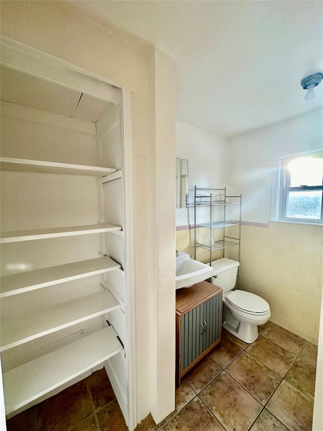 bathroom with tile patterned flooring, vanity, tile walls, and toilet