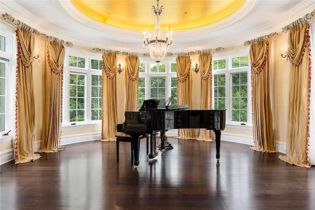 living area featuring a tray ceiling, dark wood finished floors, an inviting chandelier, and ornamental molding