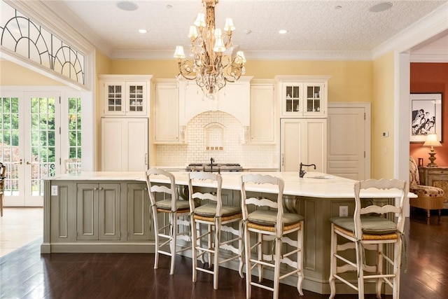 kitchen featuring french doors, light countertops, premium range hood, a large island with sink, and a sink