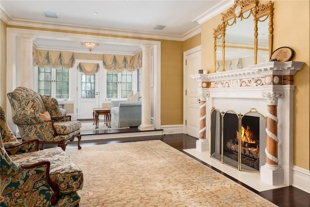 living area featuring a fireplace with flush hearth, ornamental molding, visible vents, wood finished floors, and baseboards