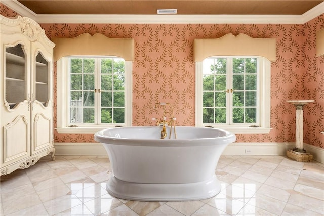 full bath featuring a freestanding tub, baseboards, ornamental molding, and visible vents