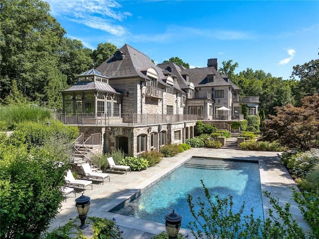 back of house with a patio area, stone siding, a gazebo, stairs, and a chimney
