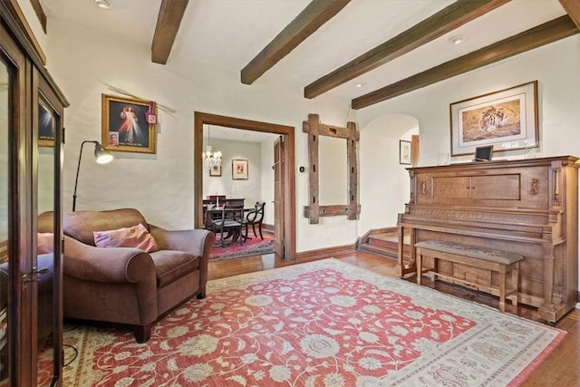 sitting room with beamed ceiling, wood-type flooring, and an inviting chandelier