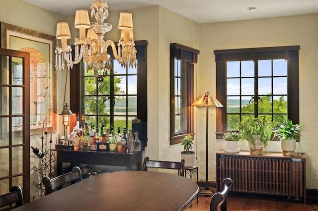 dining room with hardwood / wood-style floors, bar, radiator, and an inviting chandelier