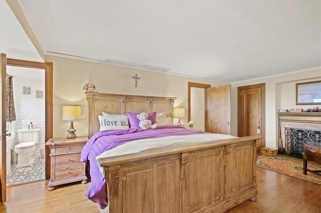 bedroom with light hardwood / wood-style floors and ensuite bath